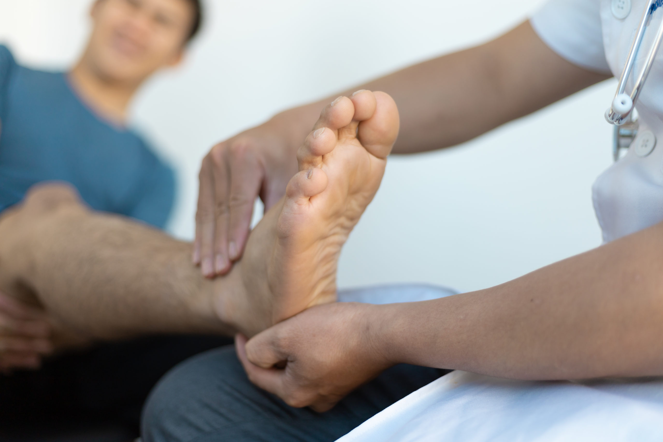 The doctor is diagnosing pain in the patient's ankle.